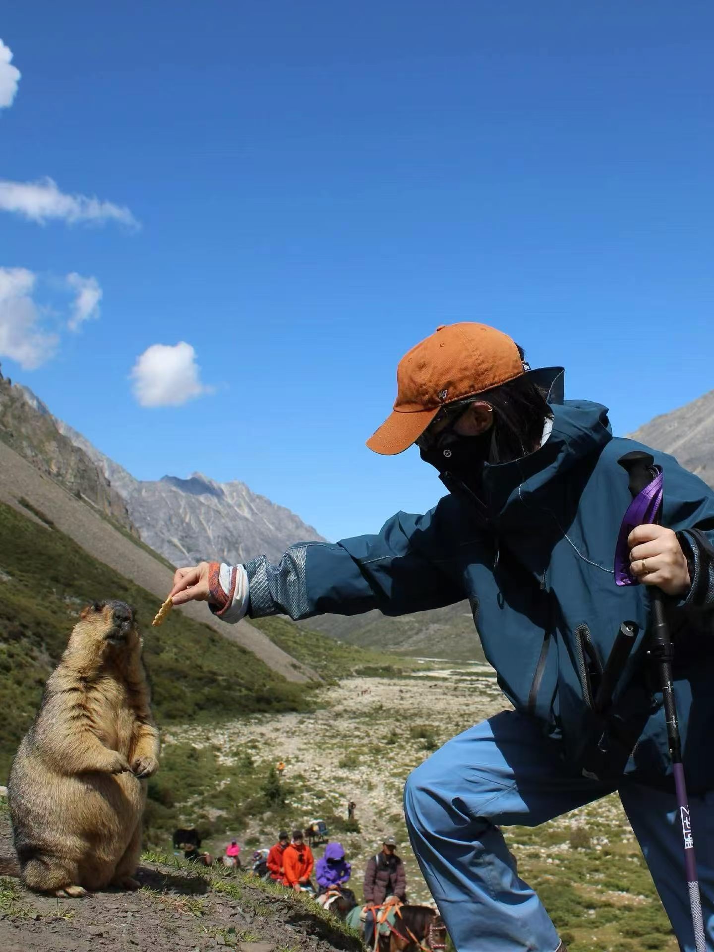 Hiker feeding marmot on mountain trail at Le Mando
